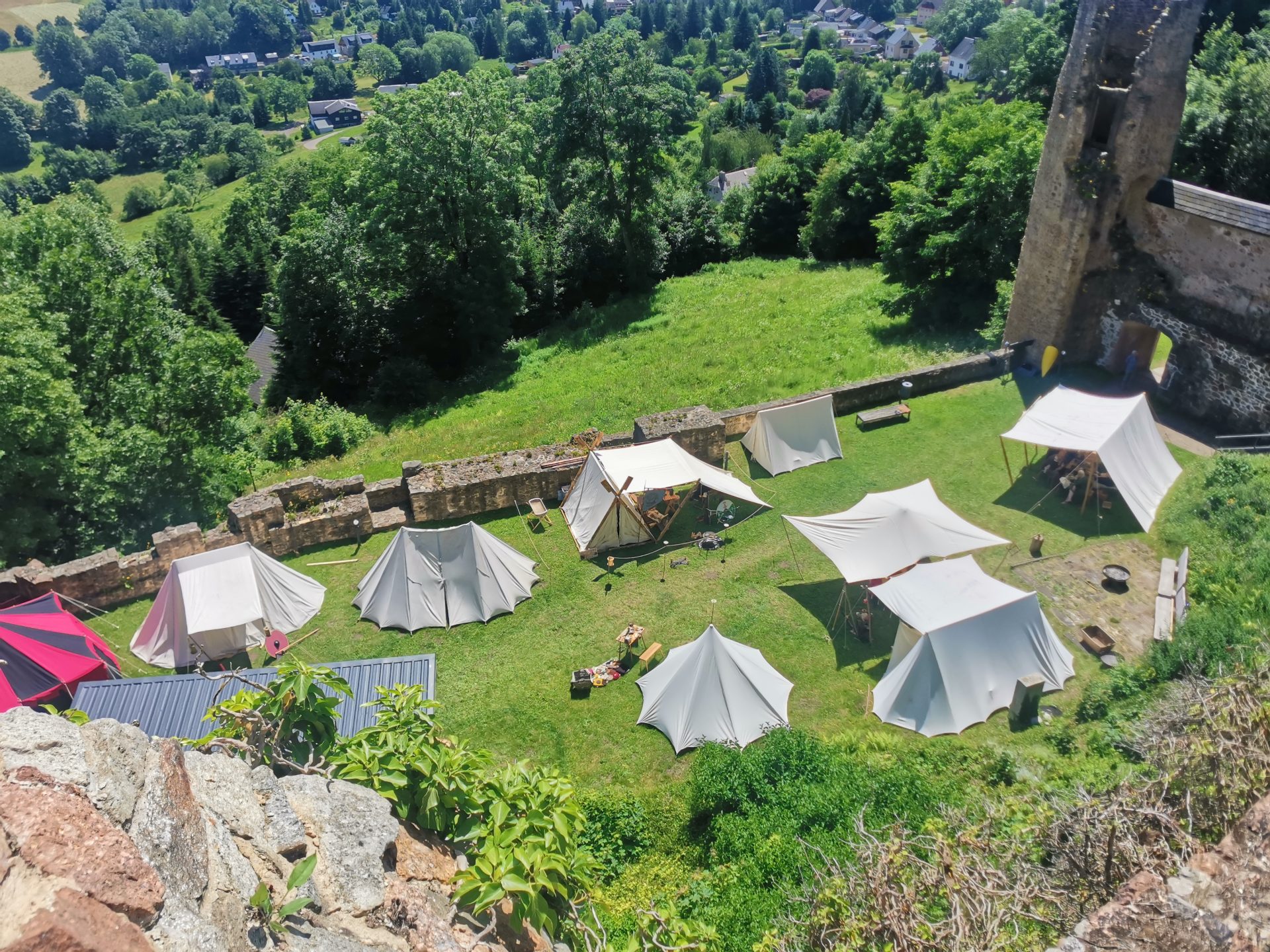 Vogelperspektive auf mittelalterliche Lagerzelte im Burghof, dahinter der Ort Frauenstein