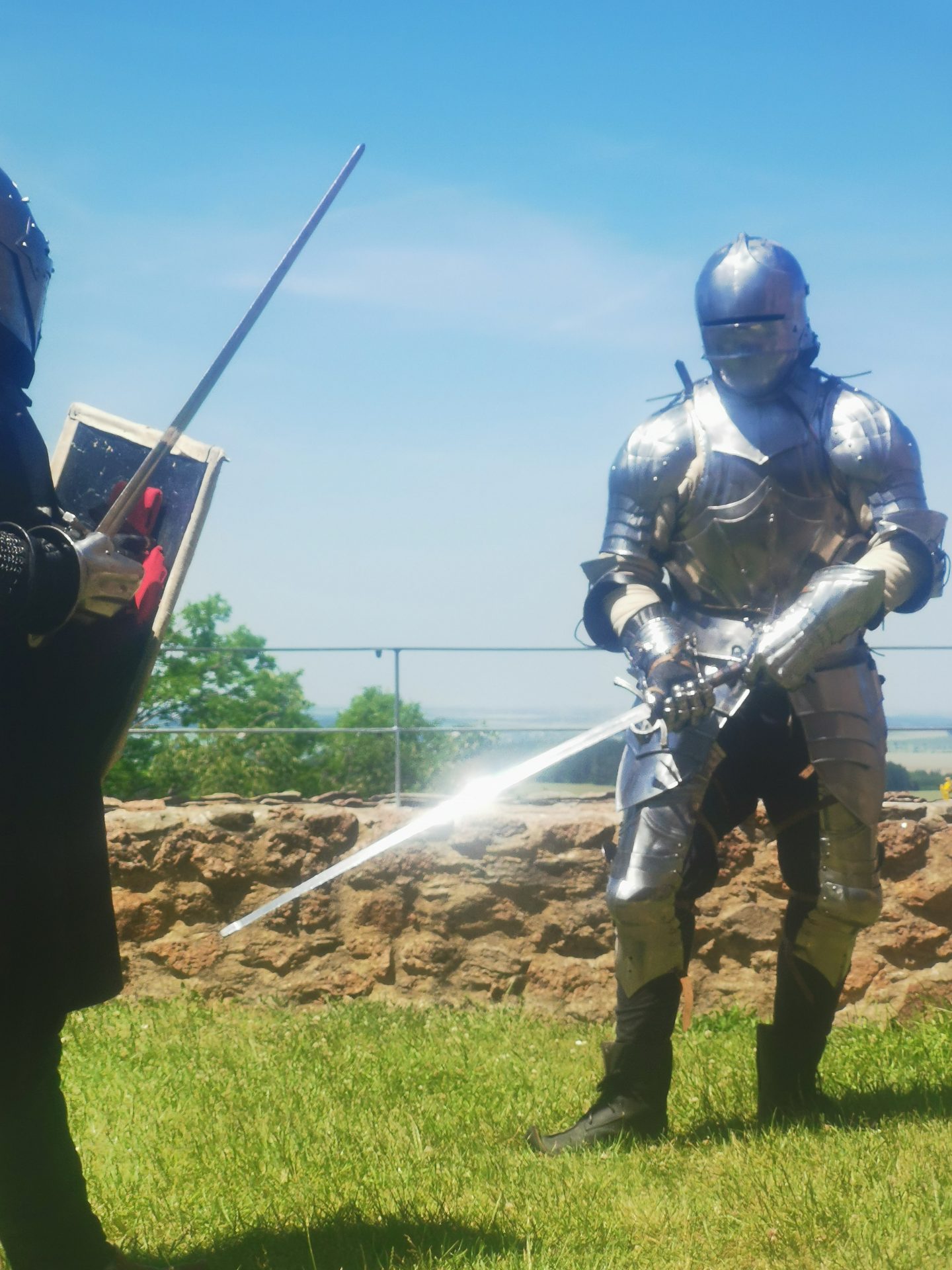 Zwei Ritter in Plattenrüstung beim Schaukampf mit Schwertern auf dem Burggelände