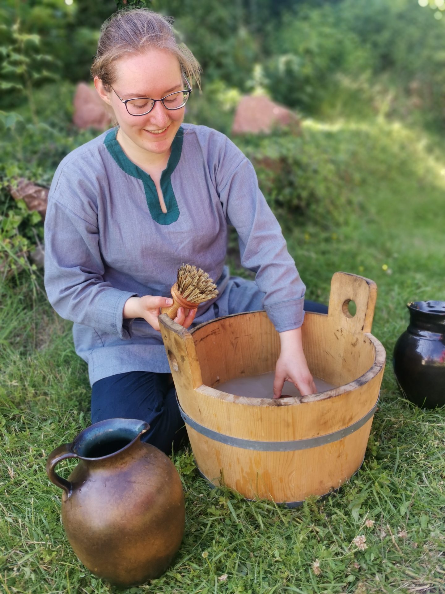 Lachende Darstellerin reinigt ein mittelalterliches Holzfass mit einer Bürste